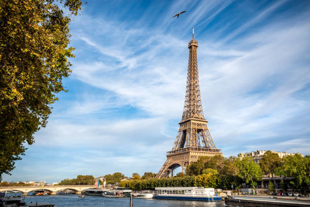 Bylandskap fra Paris med elven, bro, båter og vegitasjon i forkant av Eiffeltårenet.