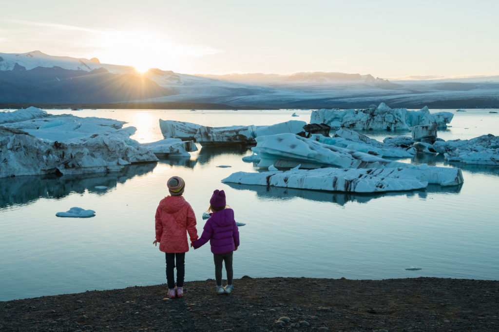 To barn som står og ser på is på havet som smelter.